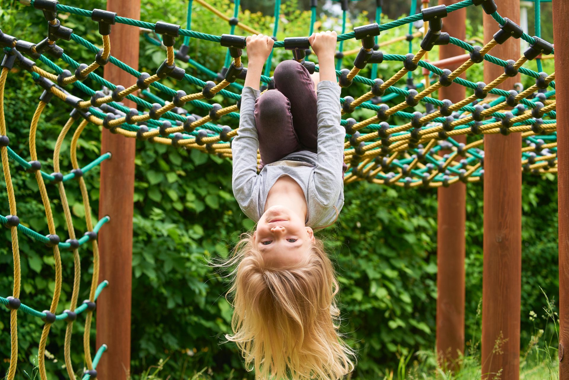 Child hanging upside down from a rope climbing net on a playground. Child hanging upside down from a rope climbing net on a playground.