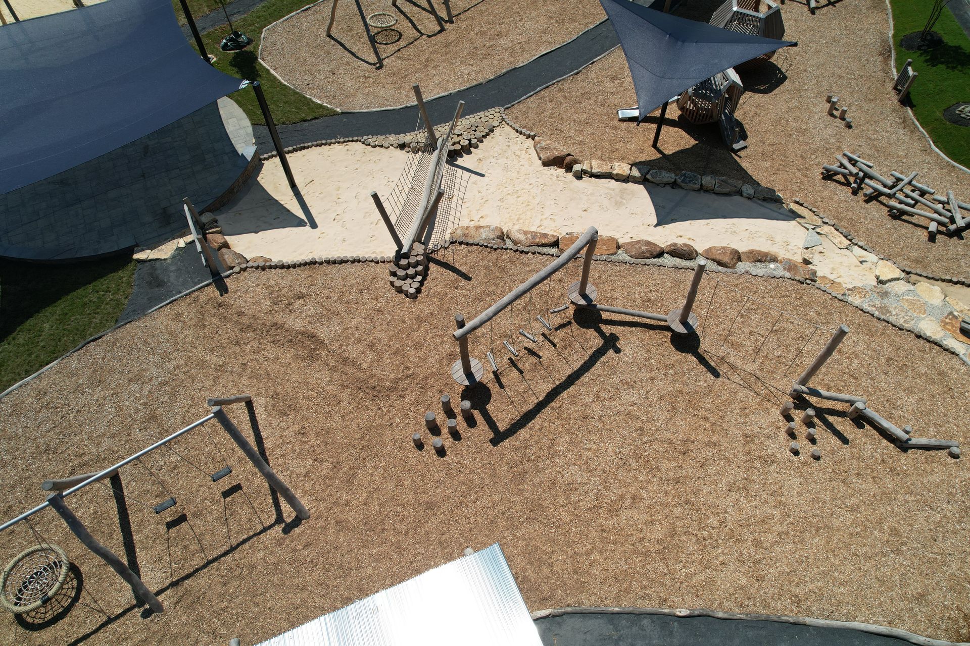 Overhead view of a playground with wooden climbing structures and wood chip ground cover.
