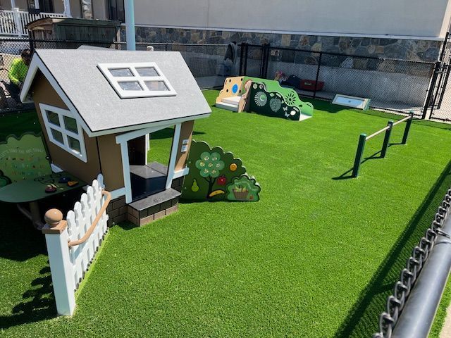 Play area with a small house, green turf, and other play structures.