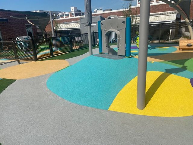 Playground with colorful rubber surfacing and climbing structure.