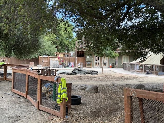 Outdoor play area with wood fences, a building, and trees.