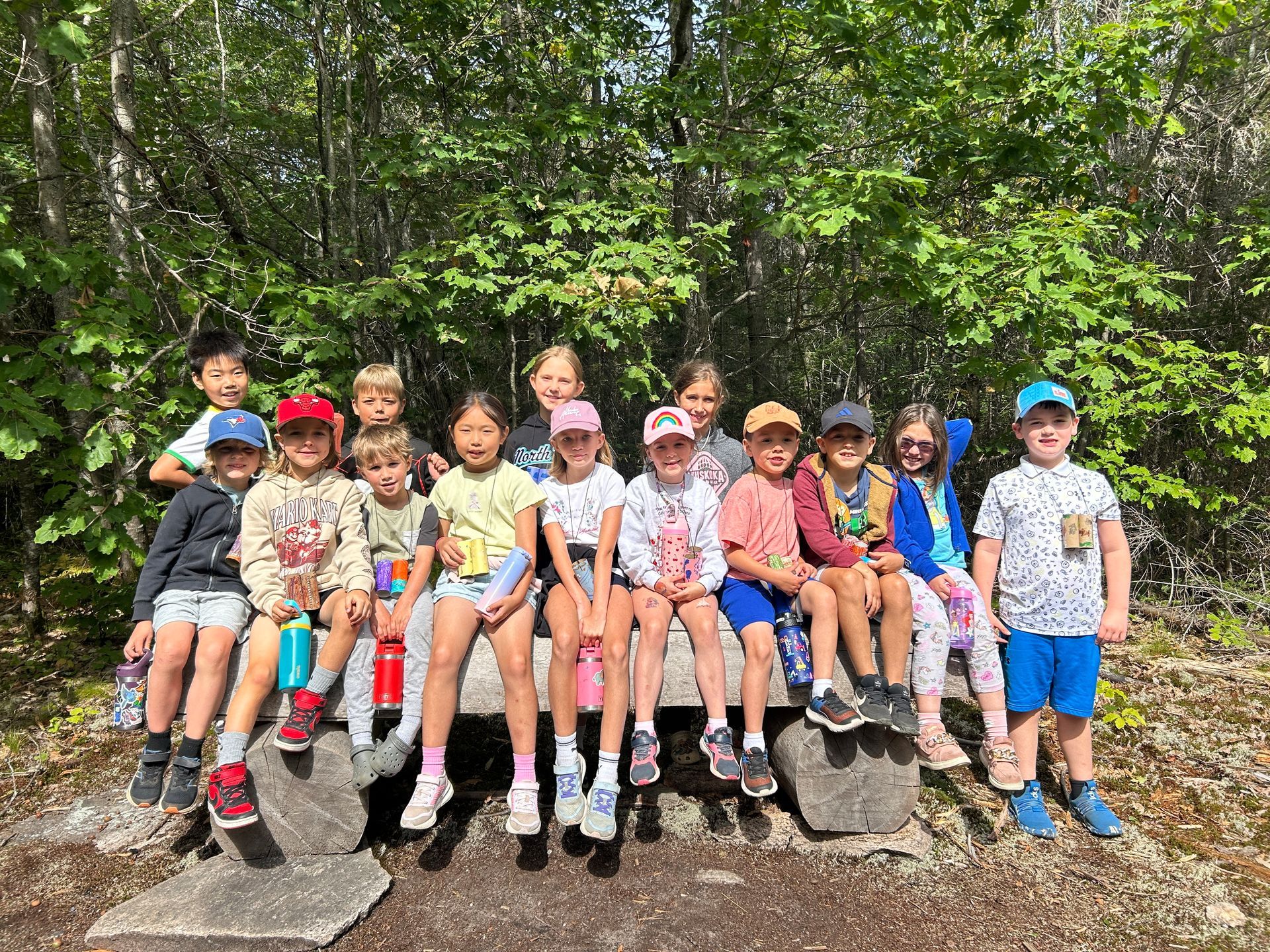 Children sitting on rocks in a forest, smiling at the camera.