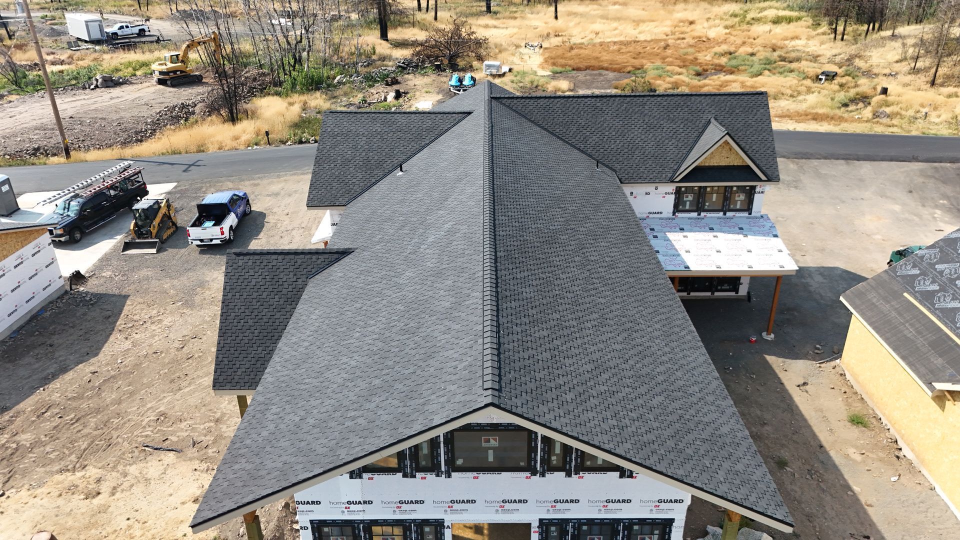 Aerial view of a house roof under construction with dark shingles and a front porch