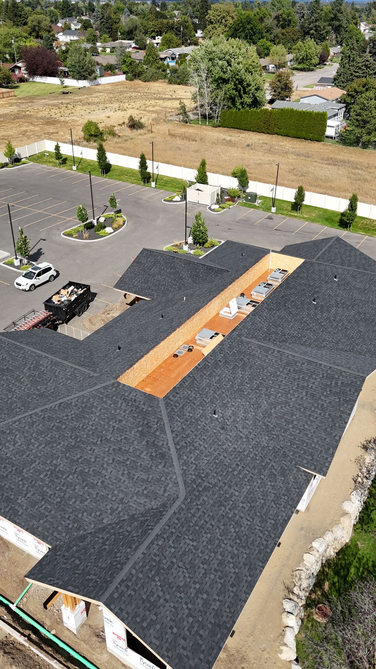 Rooftop with black gravel, a long orange skylight, and a few lounge chairs beside a landscaped yard