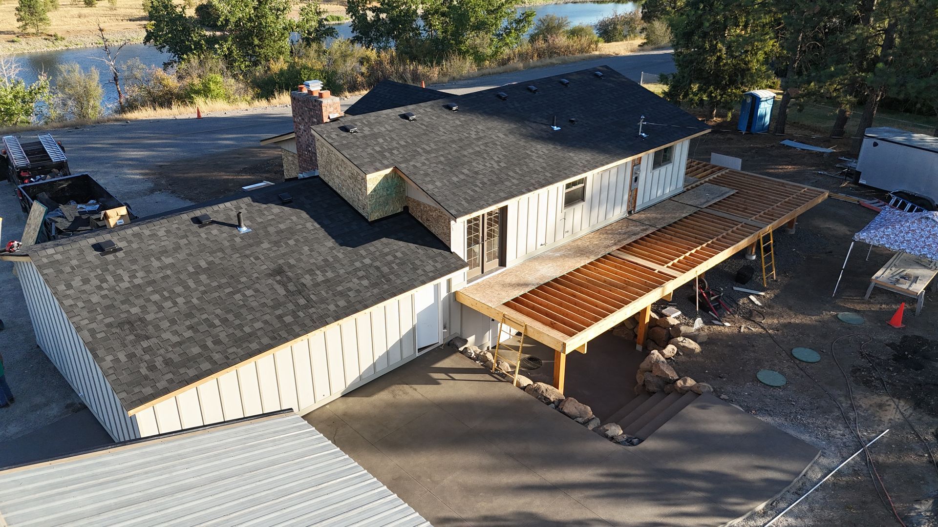 Aerial view of a house under construction with a covered patio and partially finished siding.