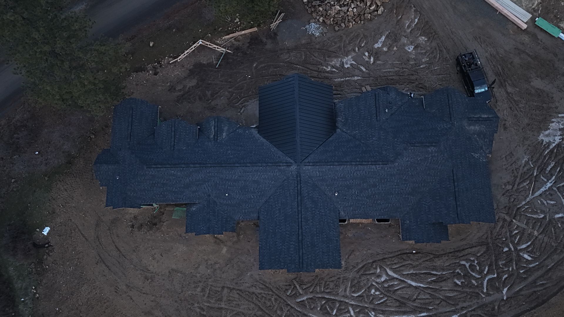 Blue rooftop seen from above, surrounded by trees and dirt ground.