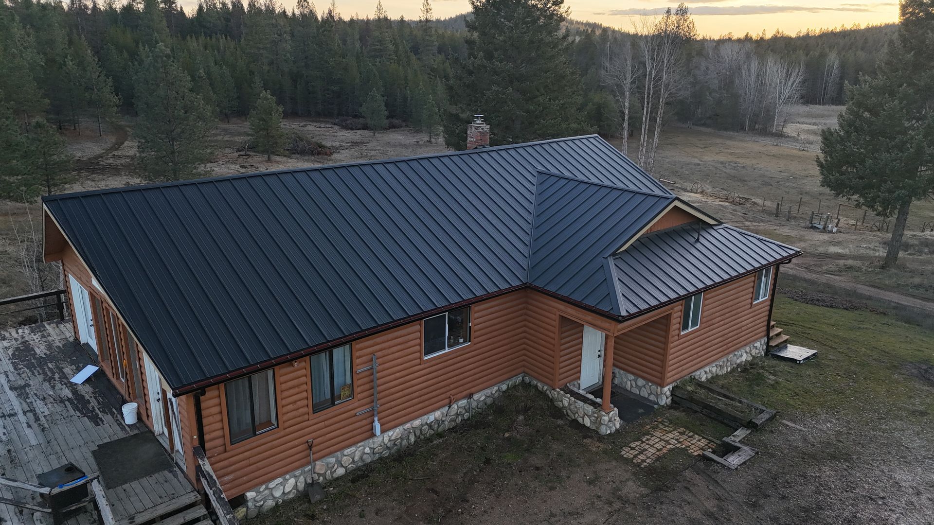 Rustic orange house with black roof in a wooded rural landscape at dusk