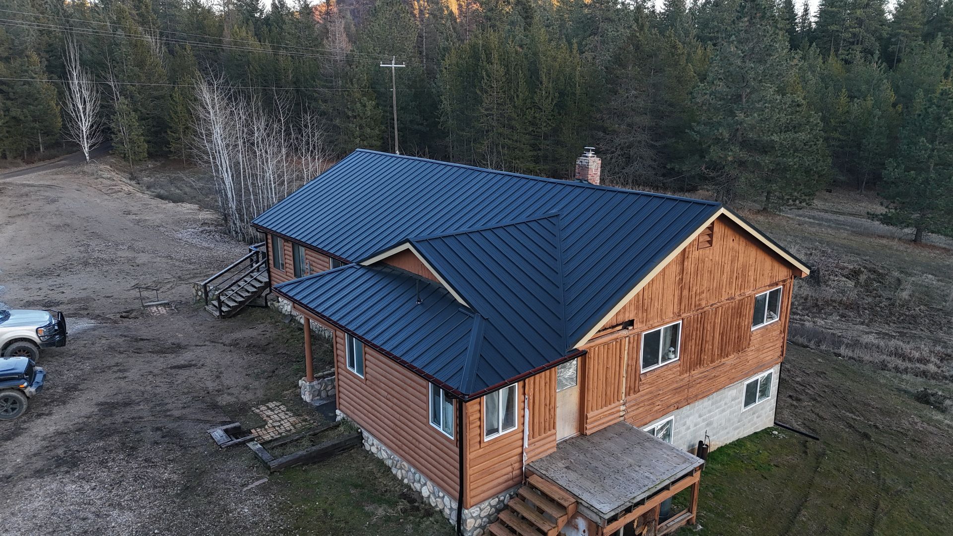 Two-story orange house with black roof in a wooded rural area, seen from above.