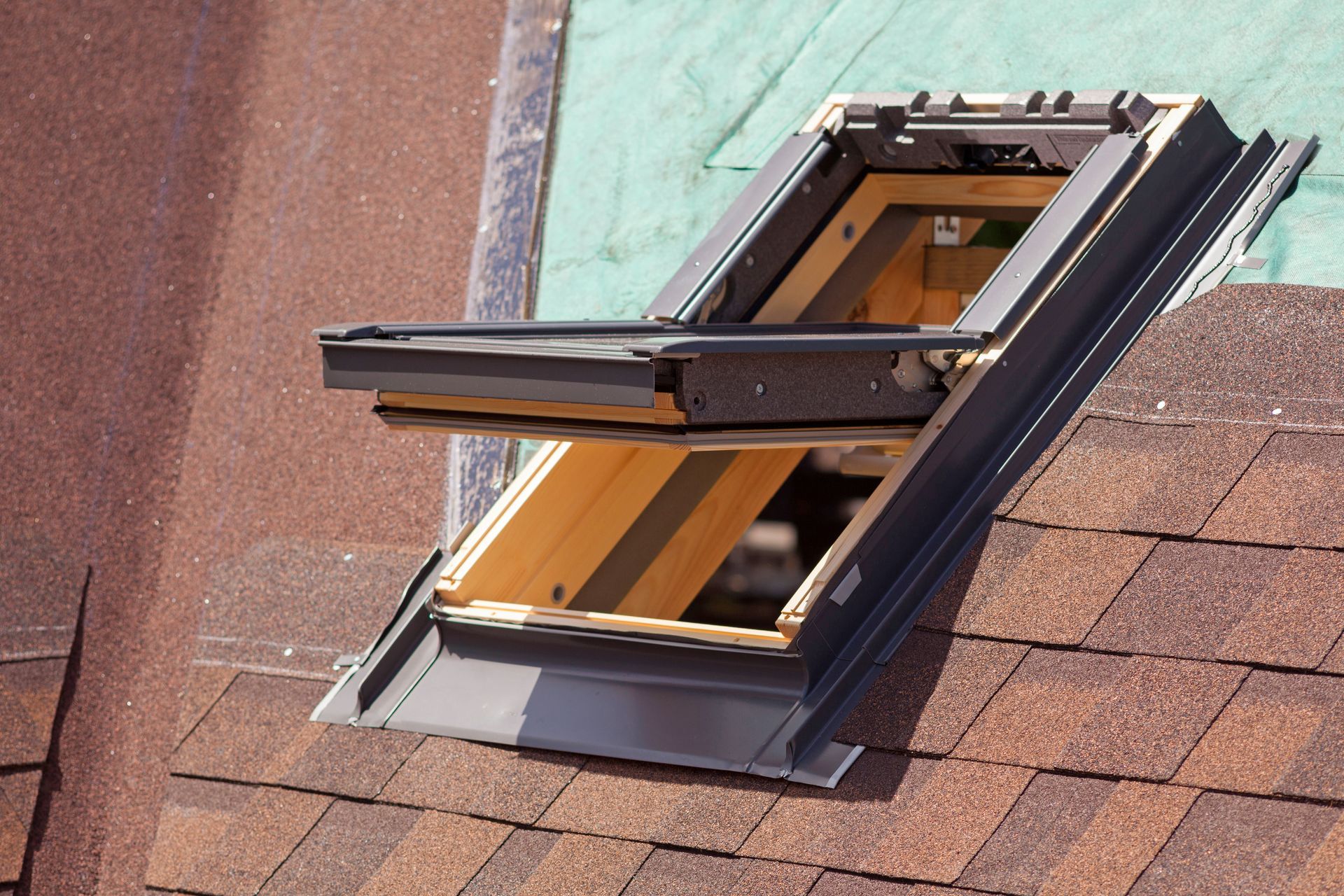 Open roof skylight window on a shingled roof, showing the interior frame.