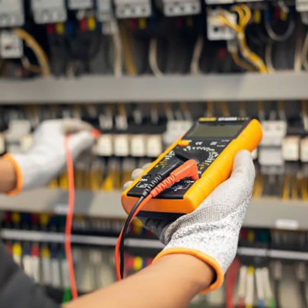 A person is holding a digital multimeter in their hand.