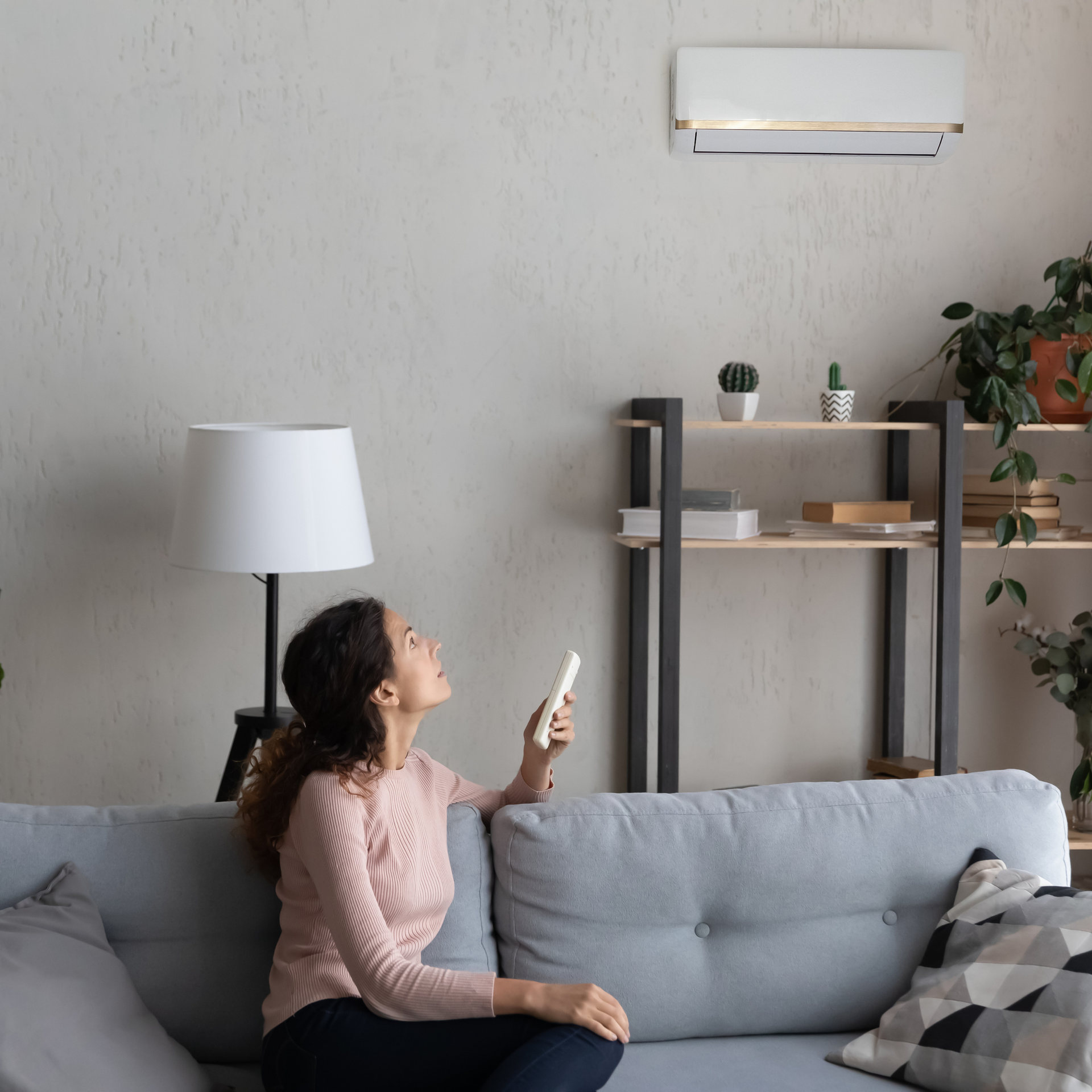 A woman is sitting on a couch holding a remote control.