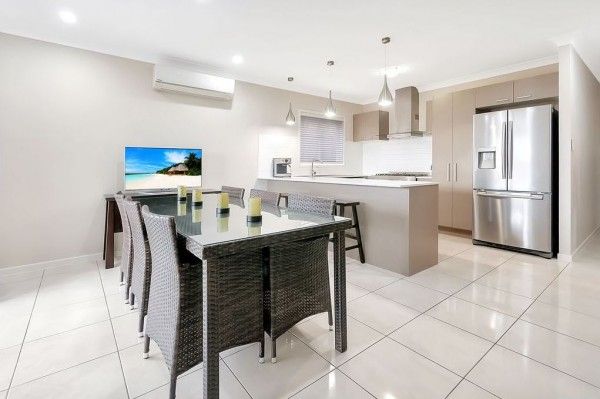 A kitchen with a dining table and chairs and a stainless steel refrigerator.