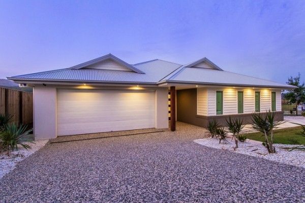 A white house with a garage and a gravel driveway