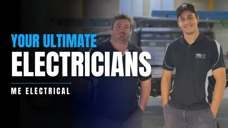 Two electricians are standing in front of a work ute in a warehouse.