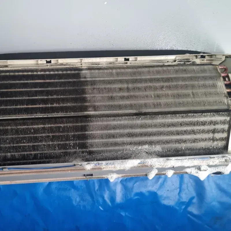 A dirty air conditioner is sitting on a blue tarp