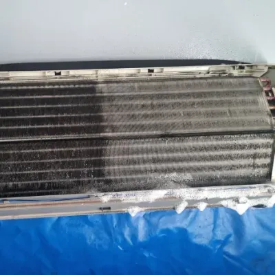A dirty air conditioner is sitting on a blue tarp