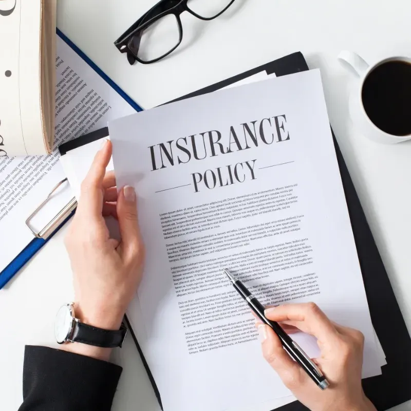 A person is reading and preparing to sign an insurance policy.
