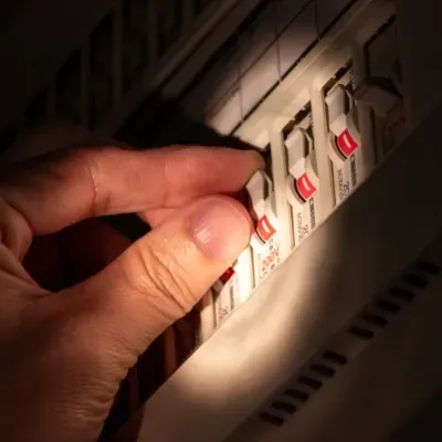 A person is flicking a switch in an electrical box.