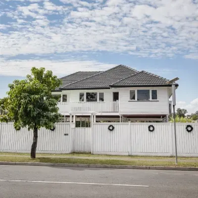 A white house with a white fence and a tree in front of it
