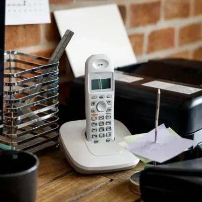 A telephone is sitting on a desk next to a printer.