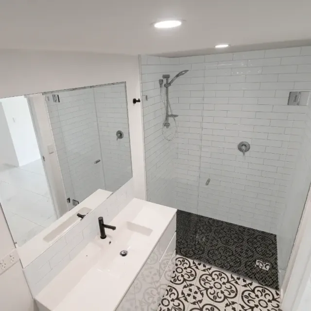 A bathroom with a sink , mirror and walk in shower.