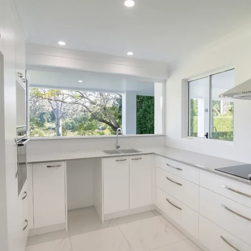 A kitchen with white cabinets and a stove top oven