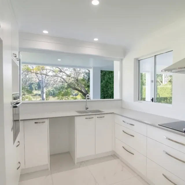 A kitchen with white cabinets and a stove top oven