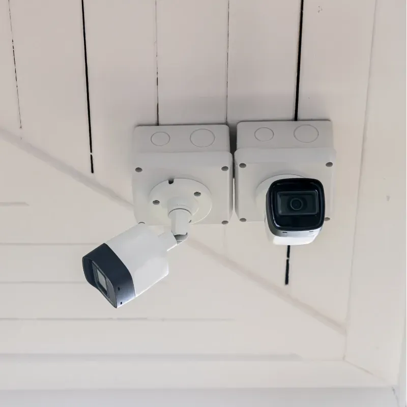 Two security cameras are hanging from the ceiling of a building.