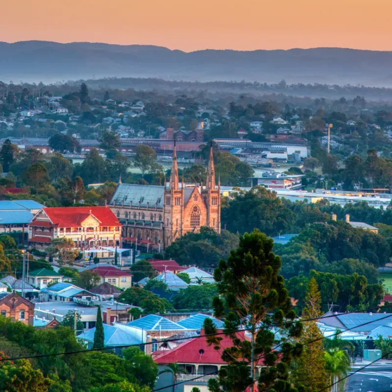 An aerial view of Ipswich city at sunset with mountains in the background.