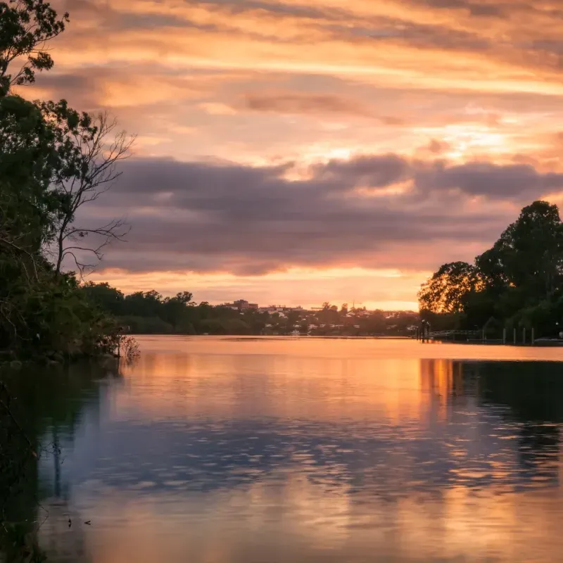 A sunset over a lake with trees in the foreground
