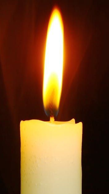 A close up of a lit candle on a black background