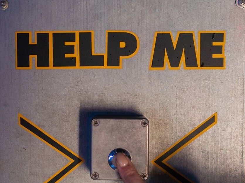 A person is pressing a button that says help me