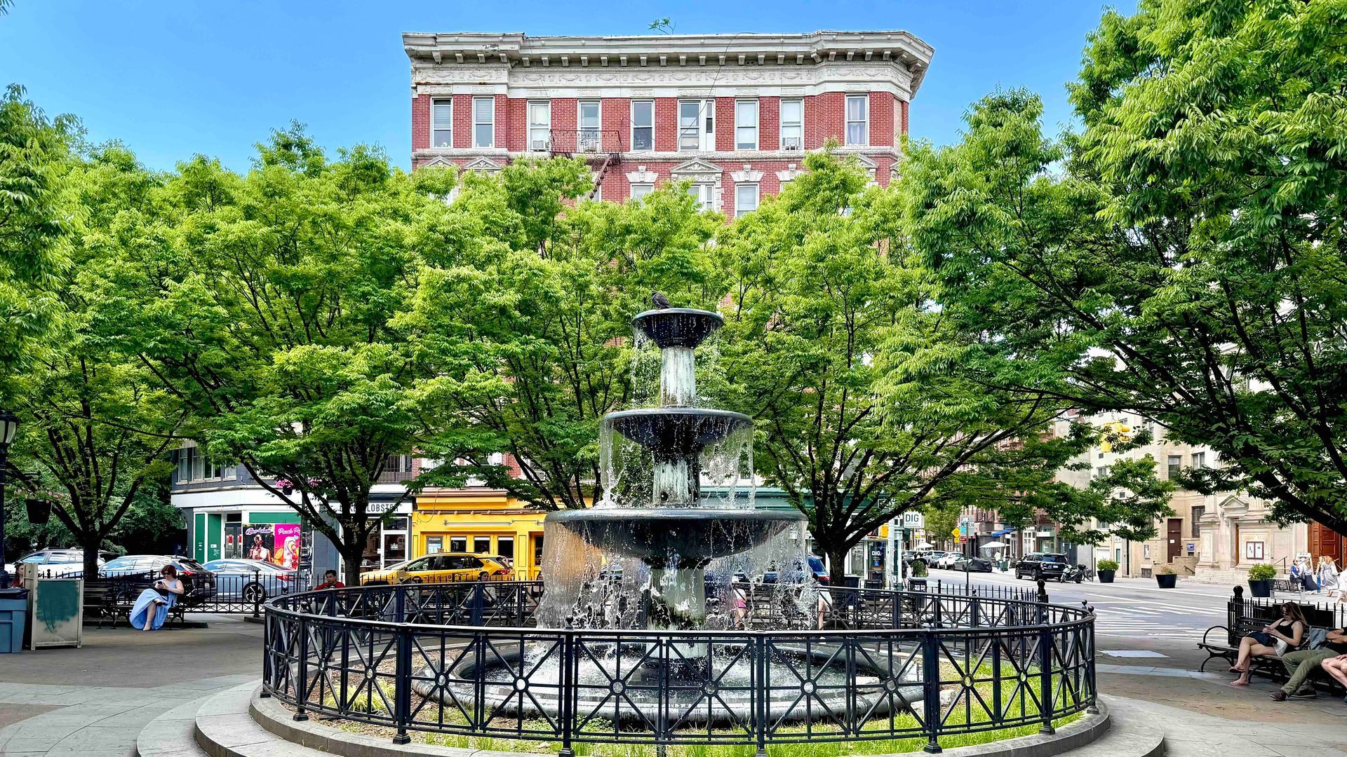 Father Demo Square fountain framed by trees and historic buildings in Greenwich Village, NYC.
