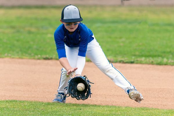 Youth catching baseball in glove.