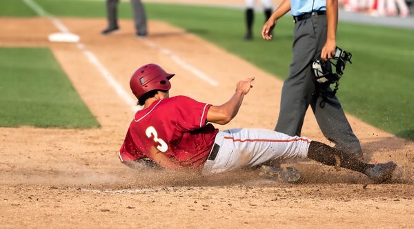 Youth baseball player sliding to base.