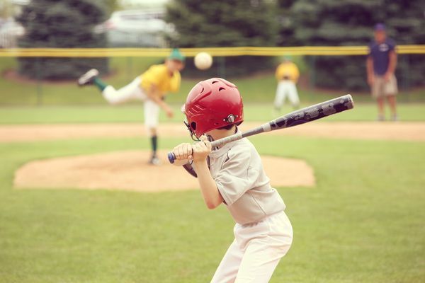 Youth up to bat with baseball being pitched