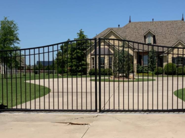 Black iron driveway gate at a luxury Oklahoma home — the result of a Legacy Fence installation