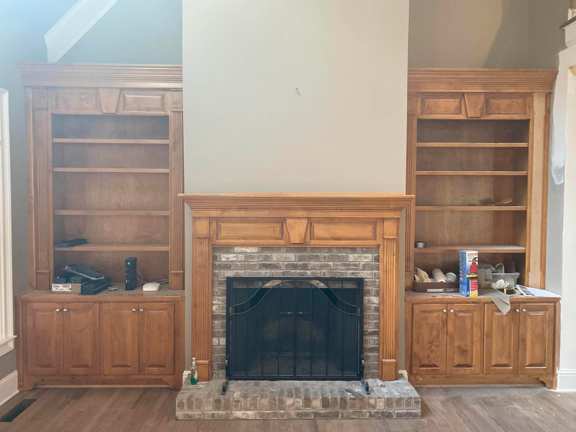 Built-in wooden bookshelves frame a brick fireplace. The mantel and trim match the bookshelves.