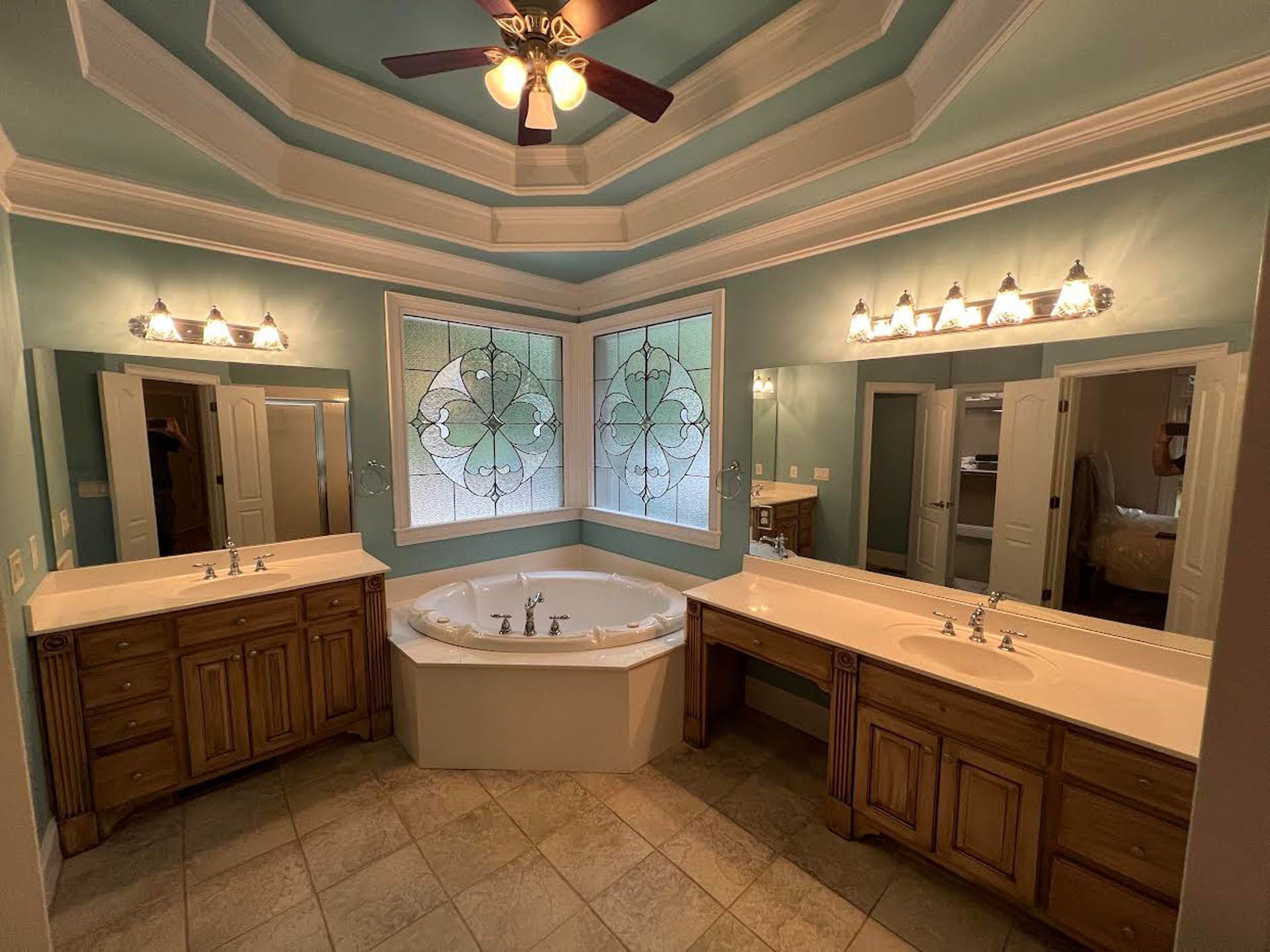 Spacious bathroom with light blue walls, a corner bathtub, and two vanity areas with sinks and mirrors.
