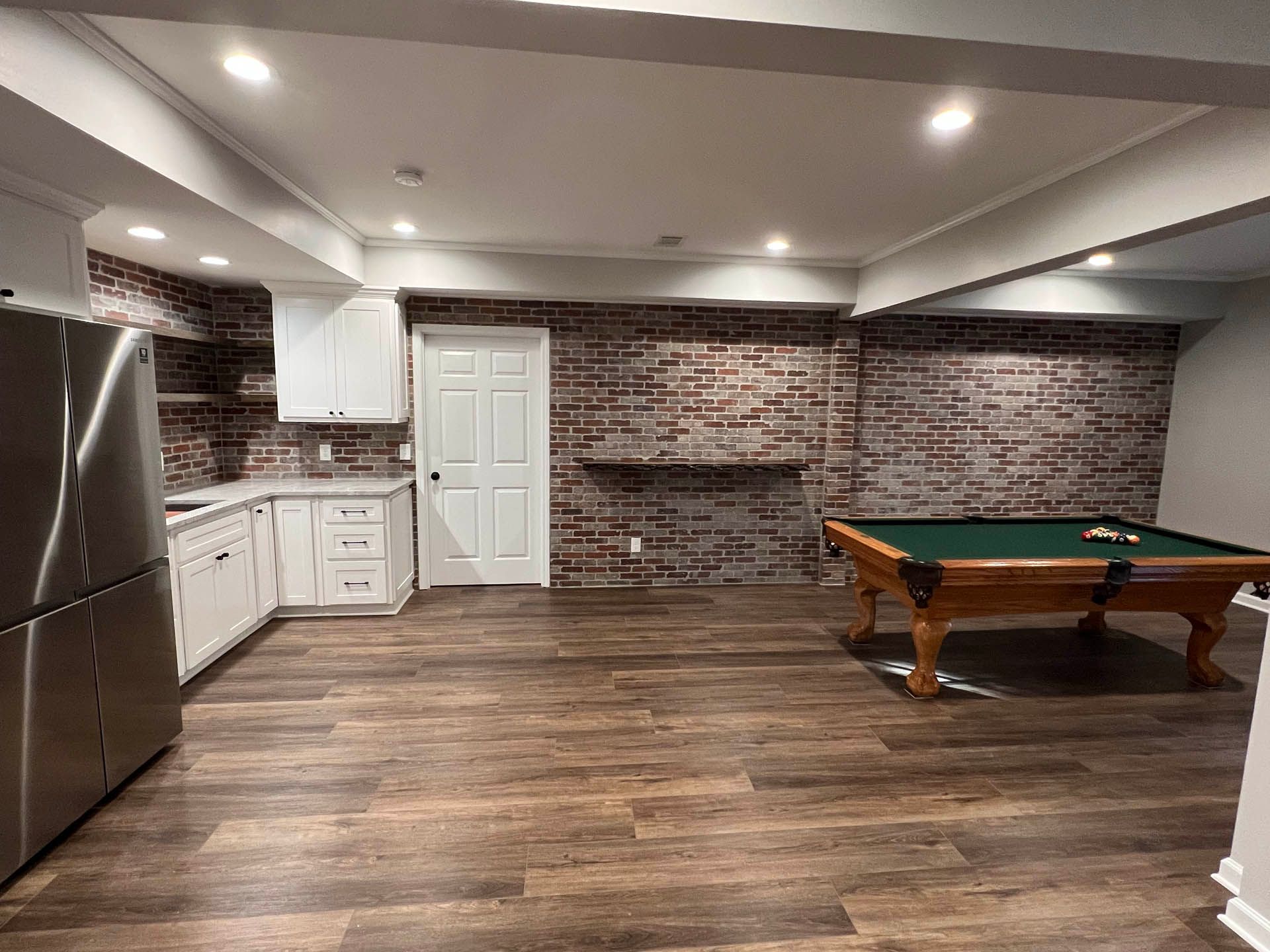 a pool table in a basement with a brick wall