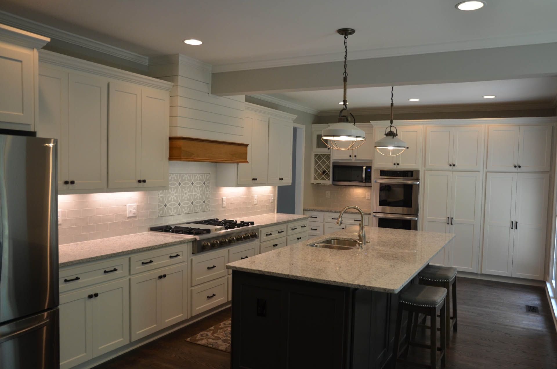 Modern kitchen with white cabinets, a dark island with granite countertop, and stainless steel appliances.