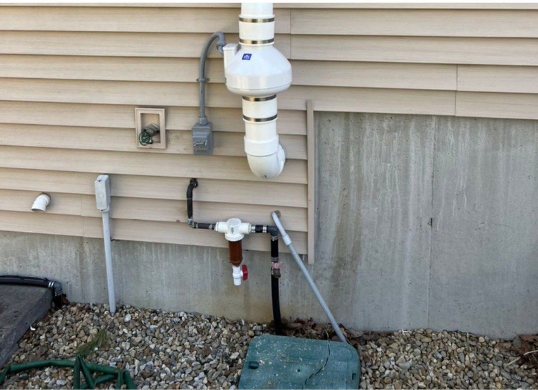 A white pipe is attached to the side of a house