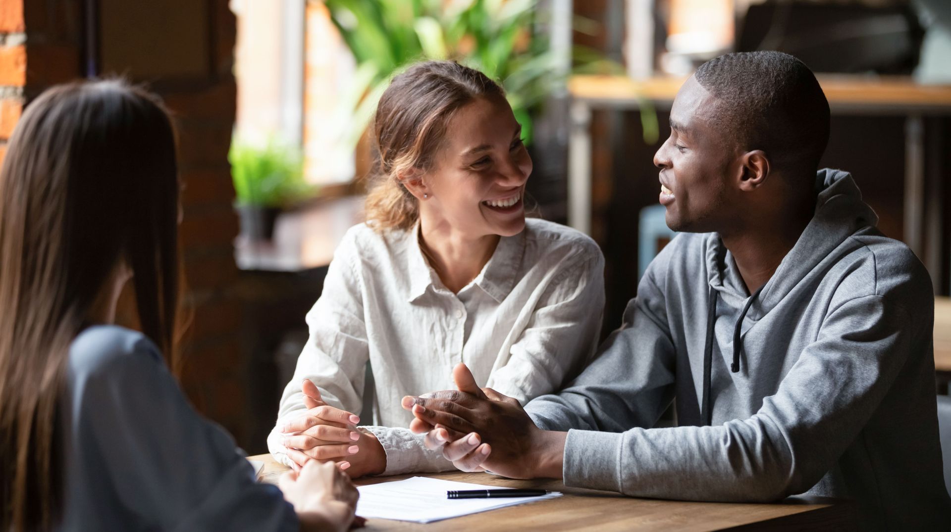 Three people at a table, smiling and talking.
