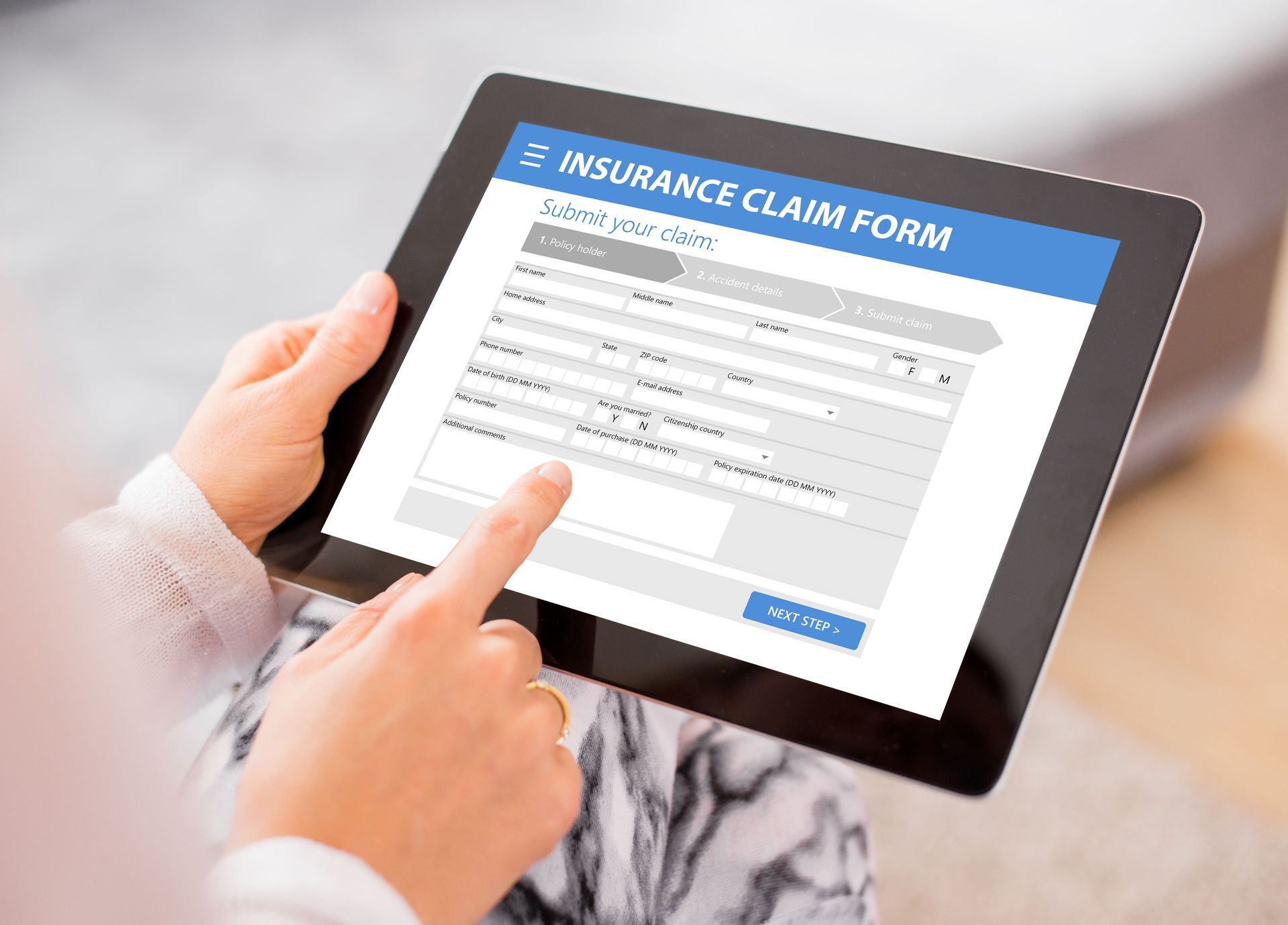 Person using a tablet to fill out an online insurance claim form.