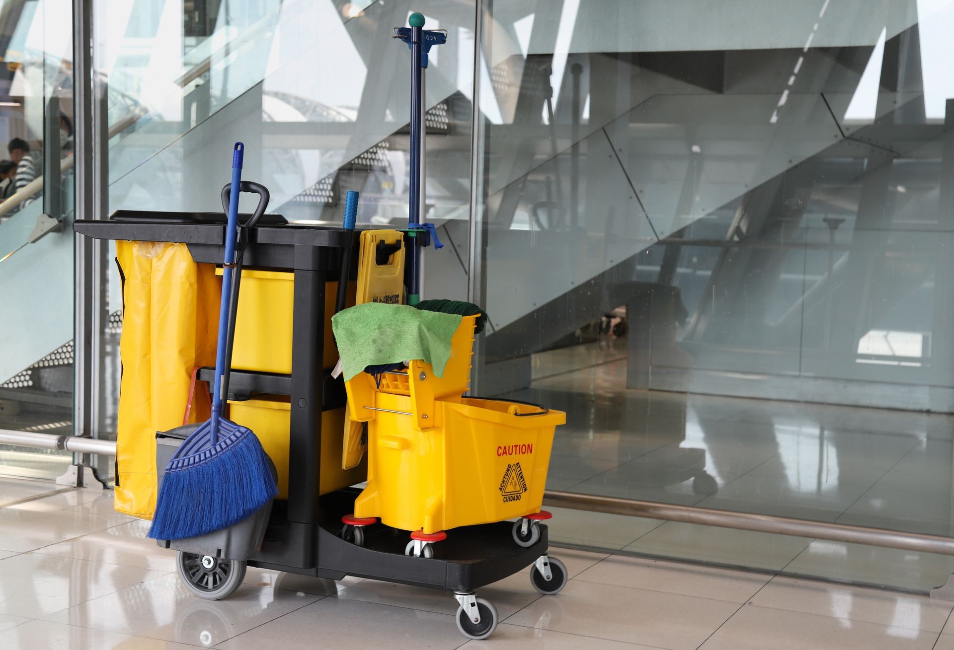Janitorial cleaning cart with mops and supplies in a glass lobby floor area
