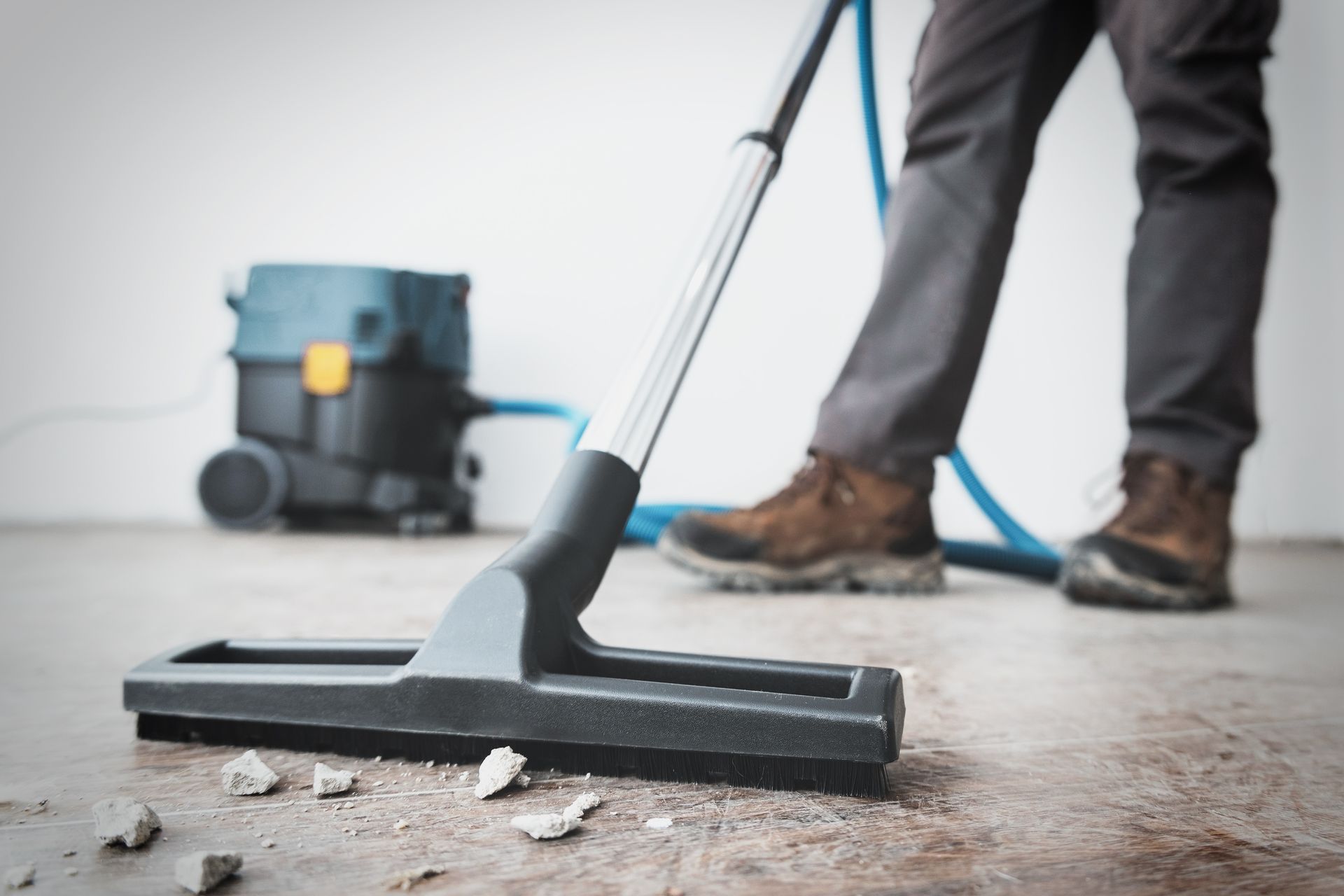 Person vacuuming a concrete floor with a wet vacuum in a workshop