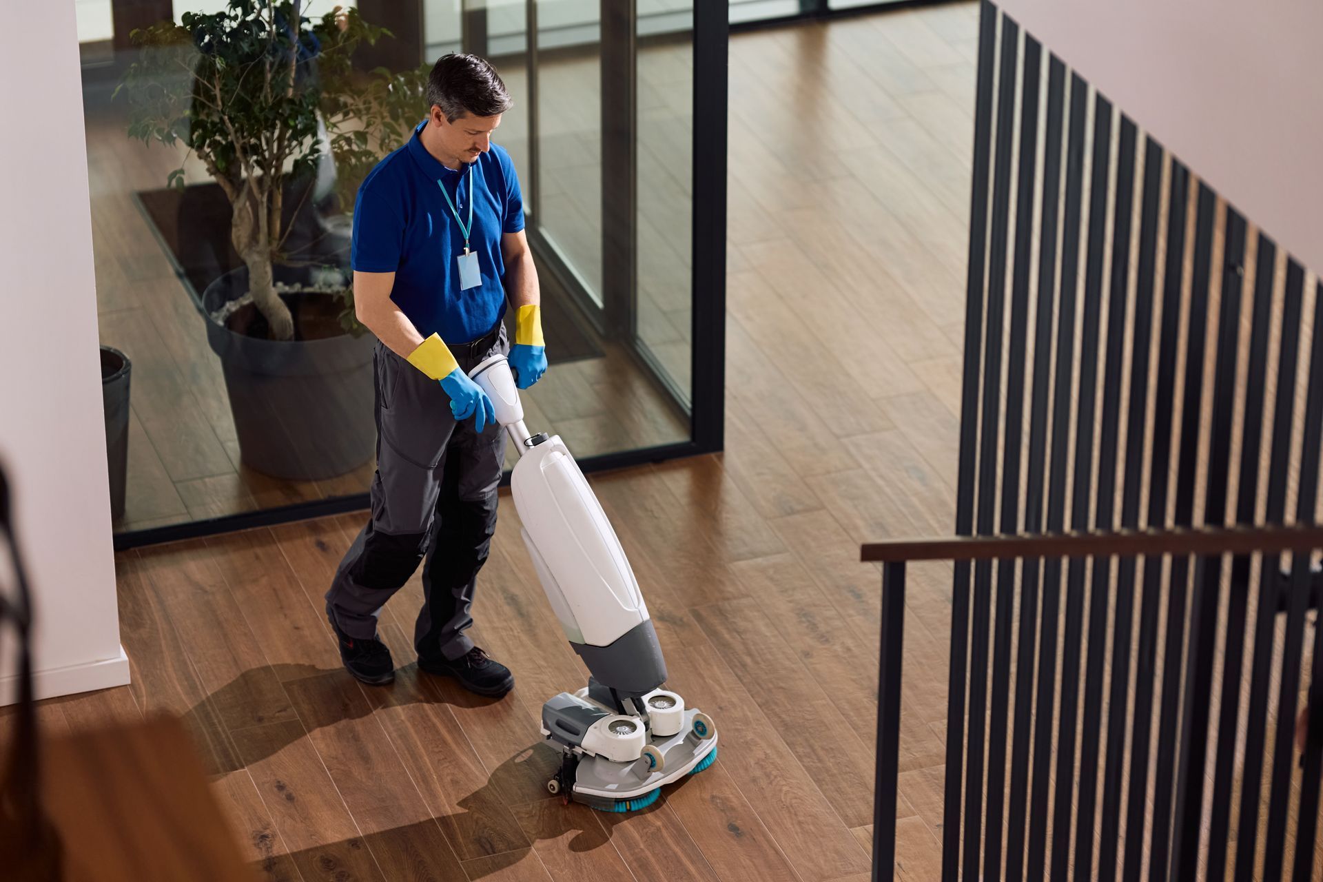 Cleaner using a floor polisher on a wooden floor indoors