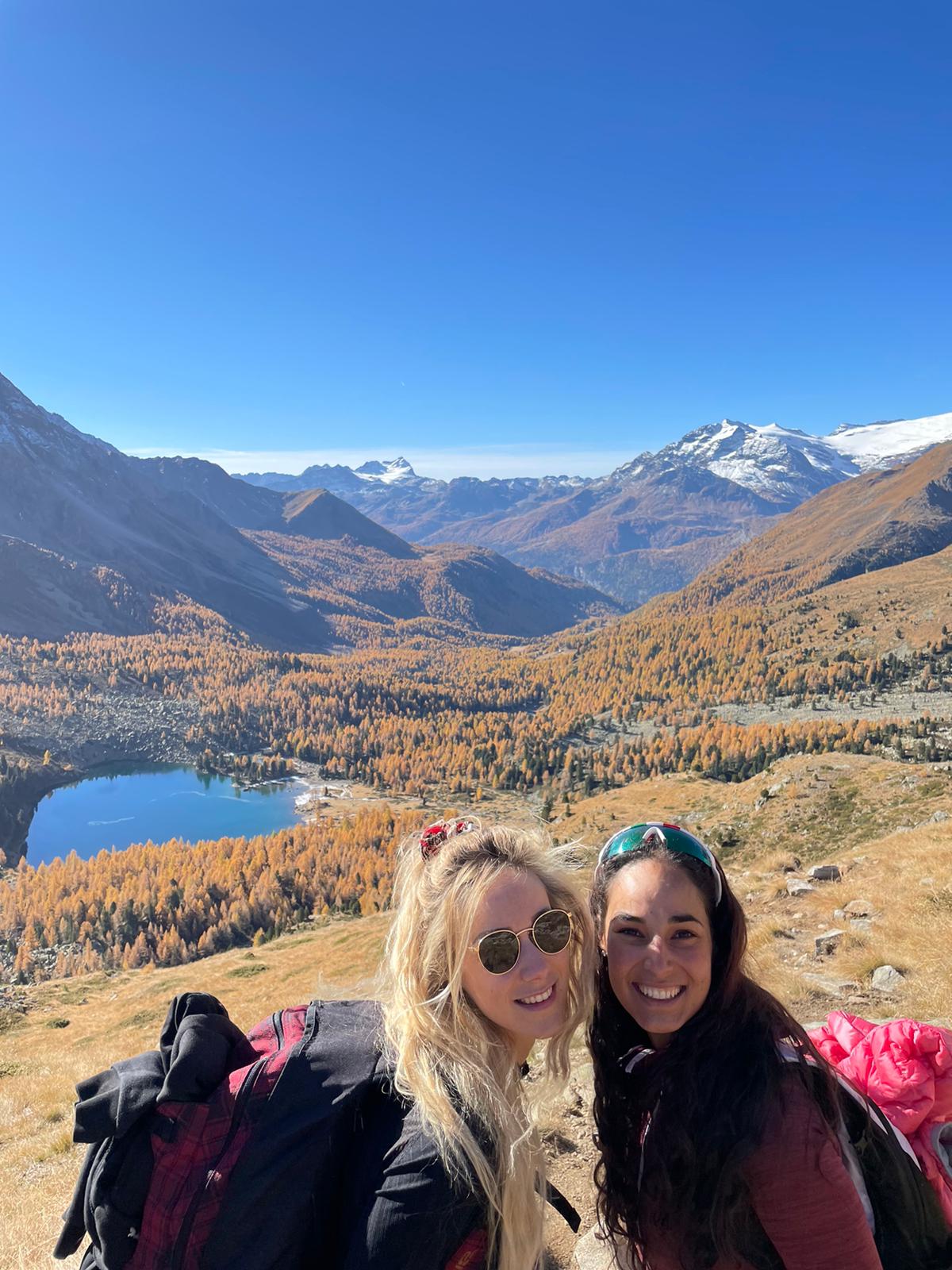 Due donne posano per una foto in cima a una montagna.