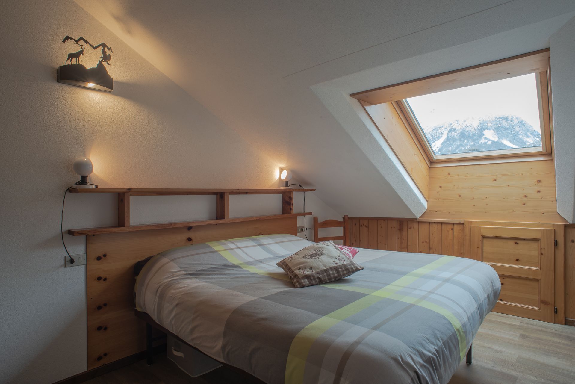 Una camera con un letto e una finestra con le montagne sullo sfondo