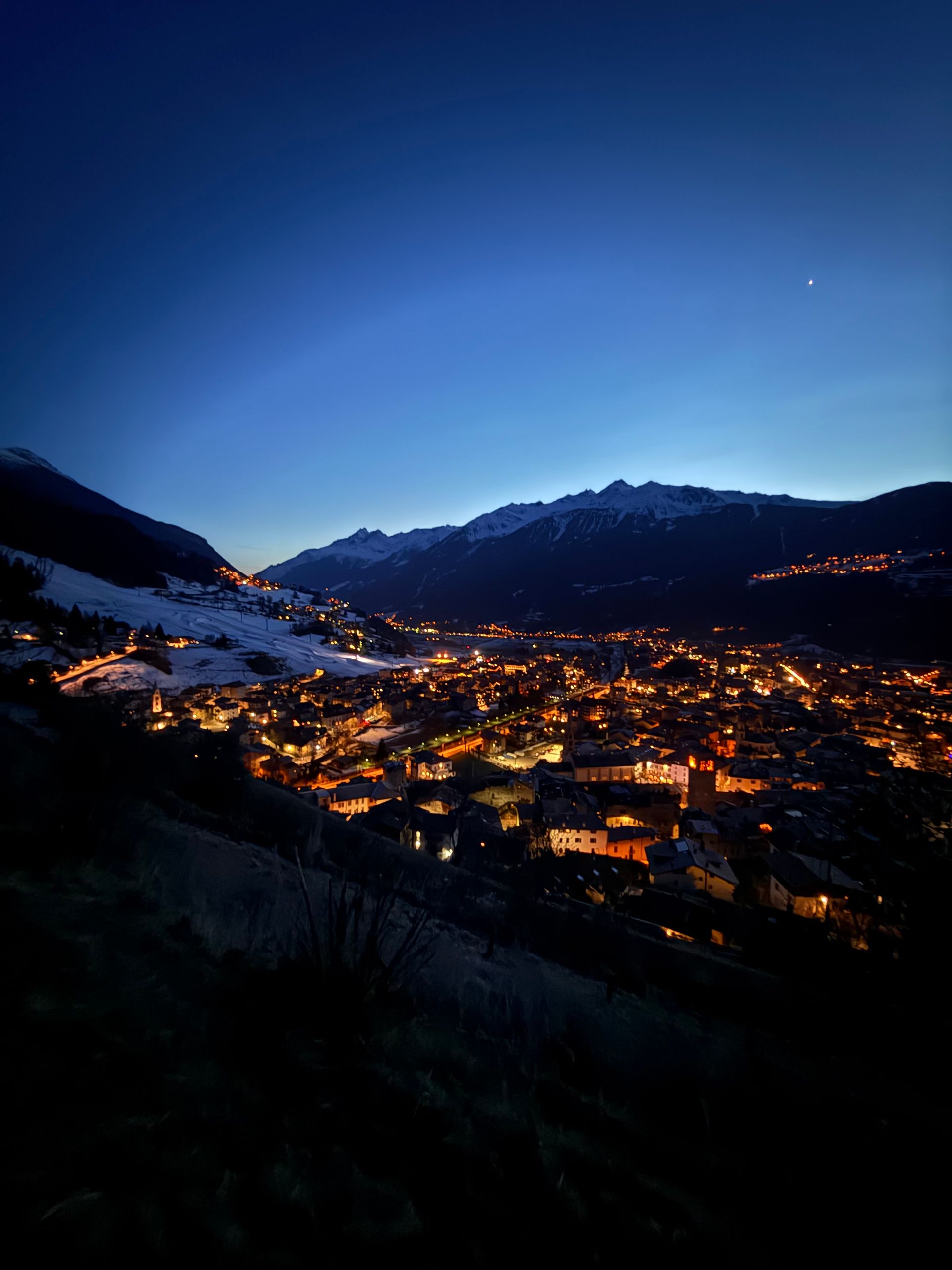 Una città è illuminata di notte con le montagne sullo sfondo